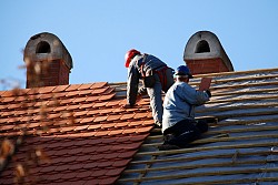 Two roofers install clay roofing tiles, a green roofing material. (Photo: majorosl/istockphoto.com)